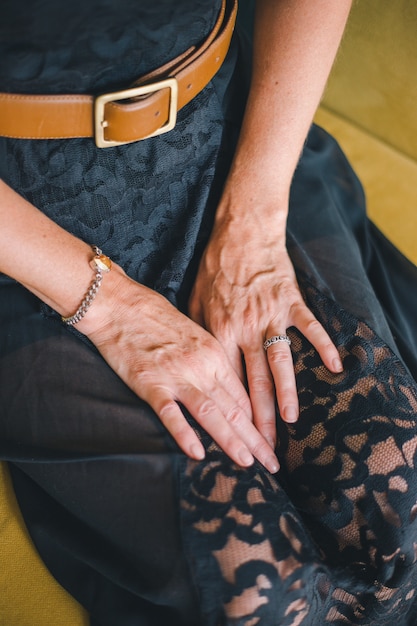 Photo close-up of the hand of an adult woman lying on her knees on a blurred background of a yellow sofa.