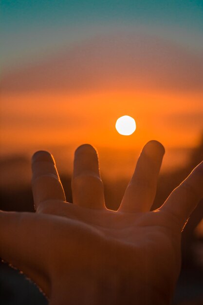 Photo close-up of hand against sun during sunset