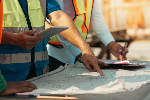 close up hand architect Engineering man in safety hardhat looking at blueprint at factory industrial facilities Heavy Industry Manufacturing Factory Prefabricated concrete walls Asian worker team