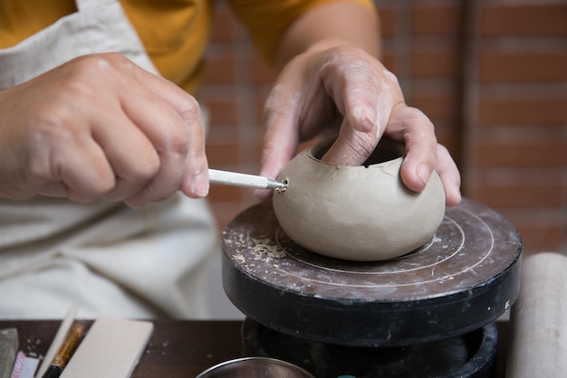 Close up hand of Asian Female using pottery wheel to make a tea pot in the workshop