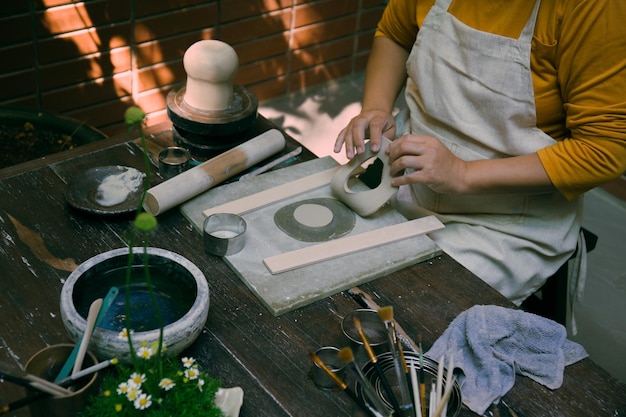 Close up hand of Asian Female using pottery wheel to make a tea pot in the workshop