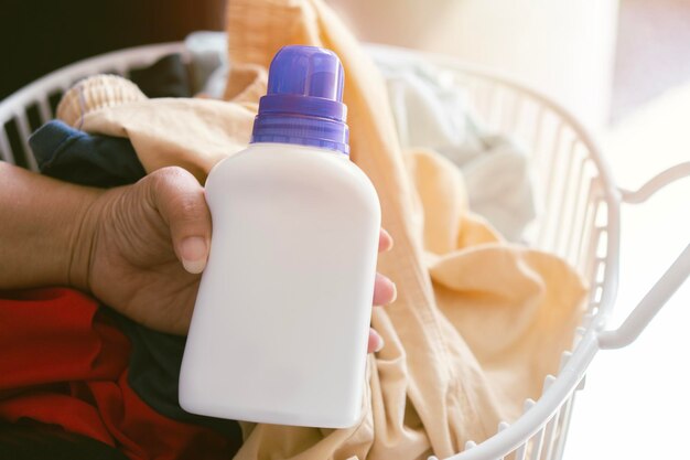 Близкая рука азиатской женщины с бутылкой моющего средства и чистыми полотенцами