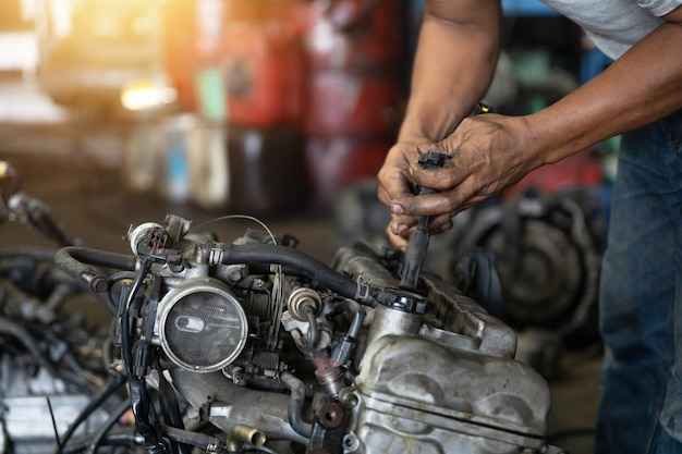 Close up hand of attractive man working hard and fix Auto mechanic on car engine in mechanics garage. Repair service