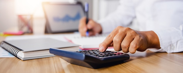 Close up hand of business man pressing on calculator to check on financial income and profit