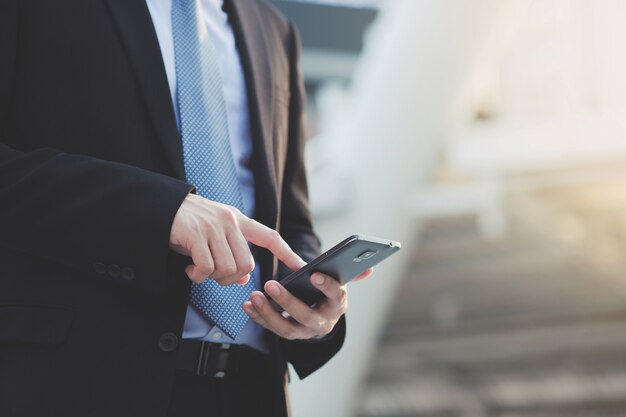 Close up hand of Business man using text mobile smart phone holding device and touching screen. or Contact Customer.