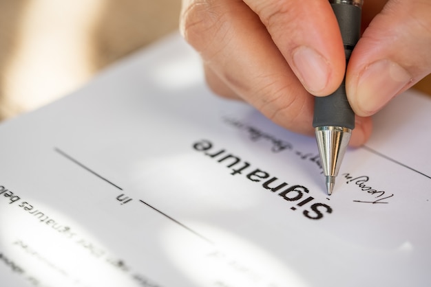 Крупным планом рука деловой женщины, держащей ручку, чтобы подписать контрактный документ