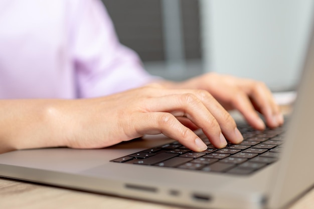 Close up hand of a business woman typing keyboard laptop computer on desk office