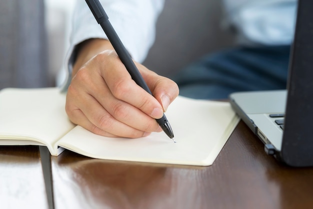 Close up hand of Businessman planning writing note and working with laptop computer