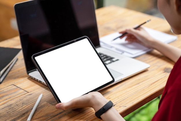 Close-up hand businesswoman holding a tablet blank white screen sitting at the office. Mock up.