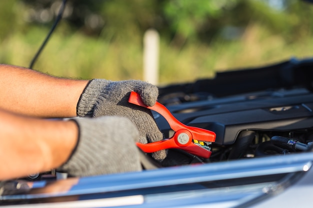 Close up hand of car technician holding cable to connect to battery