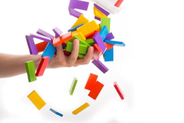 Close-up of hand catching multi colored toy blocks against white background