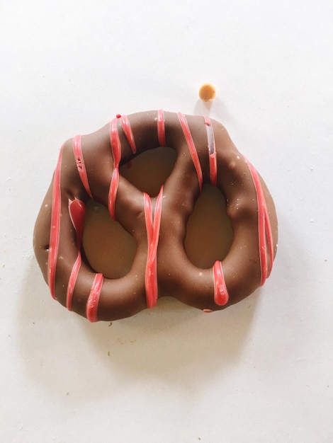 Foto close-up di un pretzel coperto di cioccolato su sfondo bianco