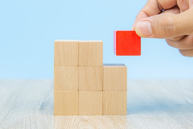 Close-up hand choose a cube shape wooden block toy stacked without graphics for Business design concept and activity for child foundation practice skills.