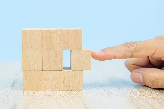 Close-up hand choose a cube shape wooden block toy stacked without graphics for Business design concept and activity for child foundation practice skills.