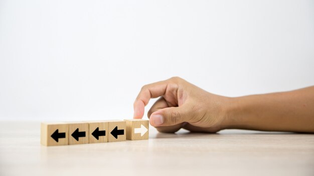 La mano del primo piano sceglie il blocco di legno con l'icona della freccia.