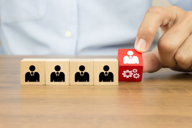 Close up hand choosing people with cog icon on cube wooden toy blocks concepts of human resources.