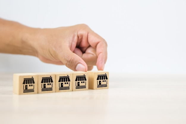 Close-up hand choosing wooden block stack with franchise icon.