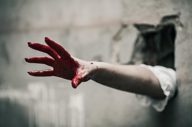 Photo close-up of hand covered in blood through wall