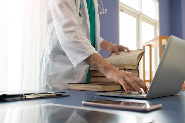 Foto chiuda sul lavoro online di conferenza del computer portatile di uso di medico della mano di fine