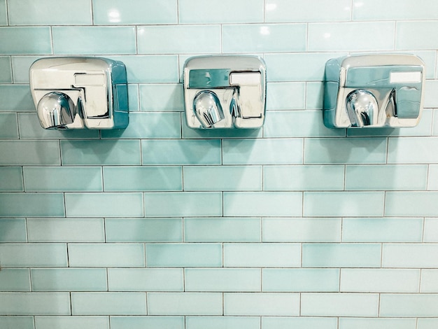 Photo close-up of hand dryers on tiled wall