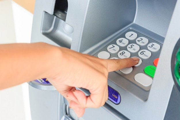 Close up of hand entering pin at an atm. finger about to press\
a pin code on a pad