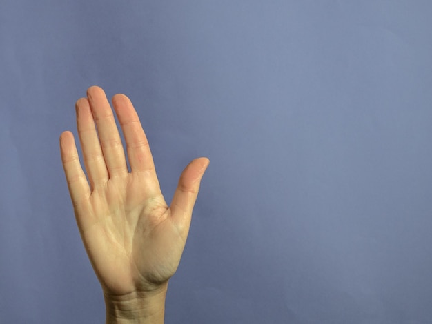 Close-up of hand gesturing against blue background