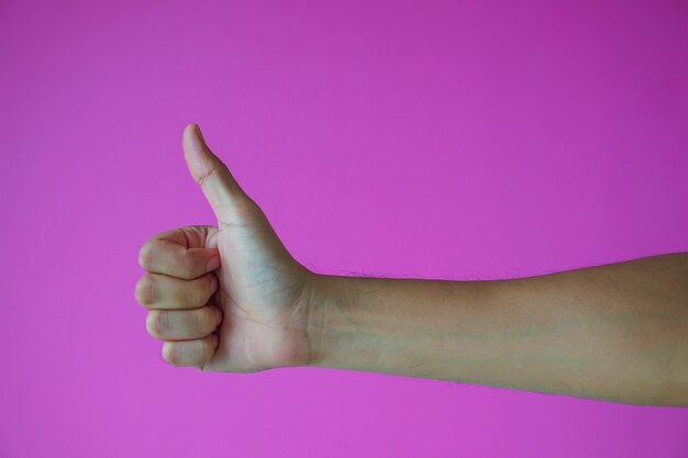 Foto close-up di mani che fanno gesti su uno sfondo rosa