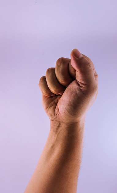 Foto close-up di una mano che gesticola il pugno contro uno sfondo viola