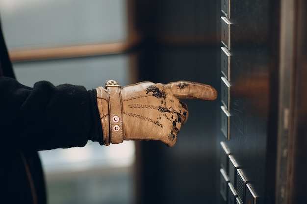 Close up of hand in glove forefinger pressing the button elevator during coronavirus pandemic covid-19 quarantine concept