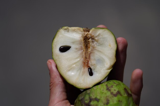 Foto close-up di una mano che tiene una mela su uno sfondo nero