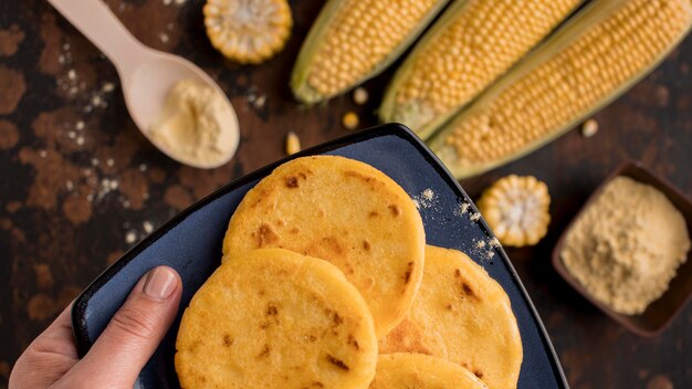 Close-up hand holding arepas plate