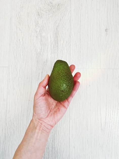 Photo close-up of hand holding avocado