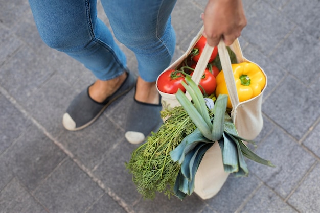 Photo close up hand holding bag with vegetables