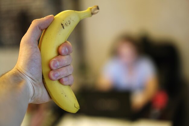 Photo close-up of hand holding banana