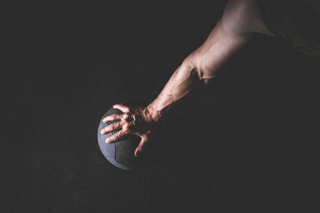 close-up of hand holding basketball over black background
