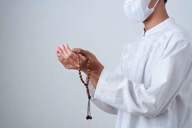 Photo close up hand holding beads or tasbih with on grey