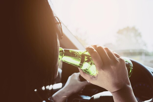 Close-up of hand holding beer bottle against sky