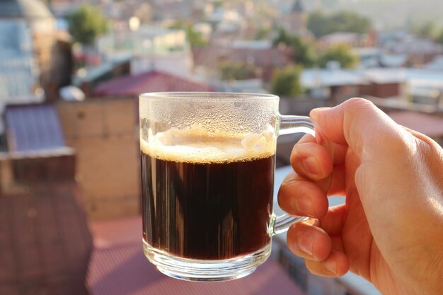 Foto close-up di una mano che tiene un bicchiere di birra