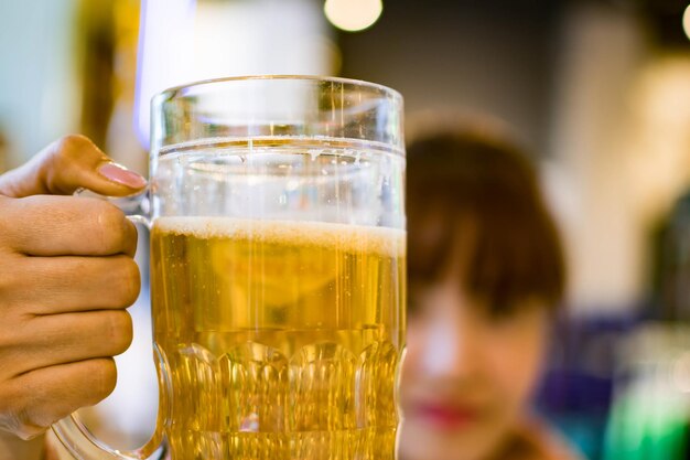 Foto close-up di una mano che tiene un bicchiere di birra