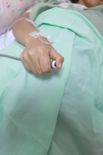 Close-up of hand holding bell on hospital bed