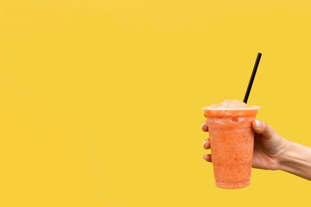 Photo close-up hand holding beverage with yellow background