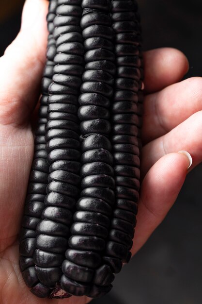 Крупным планом рука черная кукуруза