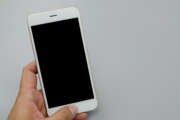 Close up hand holding black phone on on gray background.