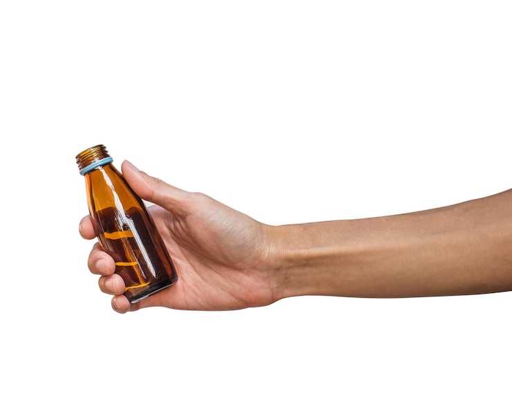Photo close-up of hand holding bottle over white background