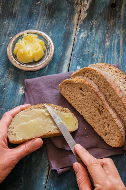 Photo close-up of hand holding bread on cutting board