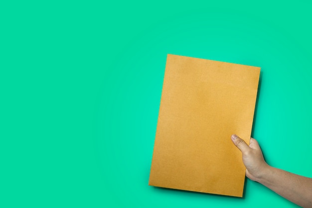 Close up of hand holding a brown envelope, A4 size paper envelope, Isolated on green background and clipping path.