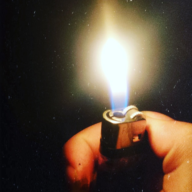 Photo close-up of hand holding burning cigarette lighter