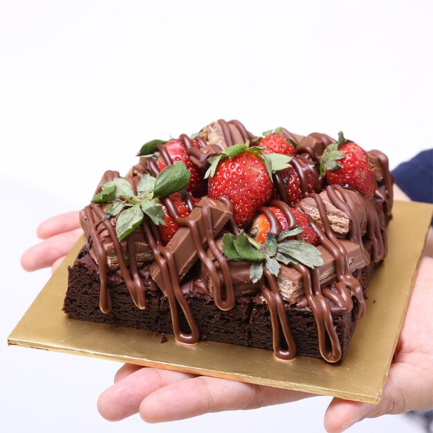 Close-up of hand holding cake against white background