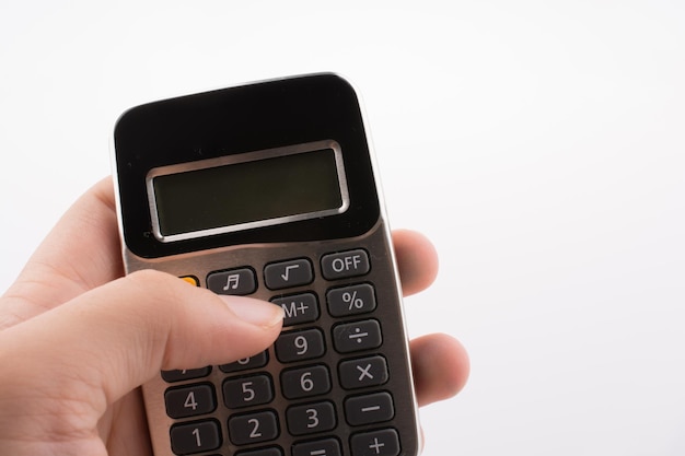 Photo close-up of hand holding calculator against white background