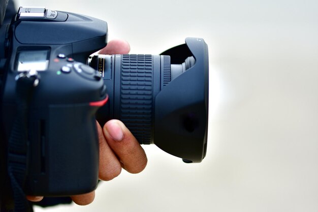 Photo close-up of hand holding camera against white background